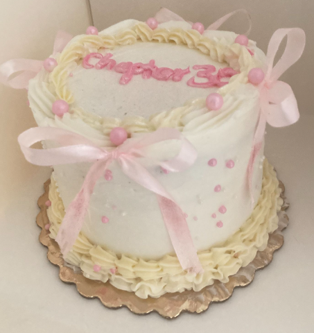 Beautiful white and pink cake with satin bows and delicate piping